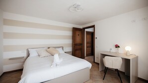 A hotel room with a bed, a desk, and a chair. There is a door leading to another room. - Private Relax Apartment: Sauna and Mini Pool (Piemonte)