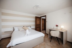 A hotel room with a bed, a desk, and a chair. There is a door leading to another room. - Private Relax Apartment: Sauna and Mini Pool (Piemonte)