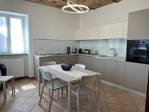 A modern kitchen with a dining table, chairs, a kettle, a coffee maker, and an oven. - Private Relax Apartment: Sauna and Mini Pool (Piemonte)