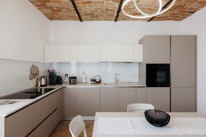 A modern kitchen with white cabinets, a black refrigerator, and a dining area with a white table and chair. - Private Relax Apartment: Sauna and Mini Pool (Piemonte)
