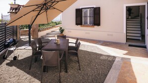 A patio with a table and chairs, an umbrella, and a barbecue grill. - Private Relax Apartment: Sauna and Mini Pool (Piemonte)