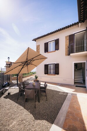 A patio with a table and chairs, an umbrella, and a barbecue grill. - Private Relax Apartment: Sauna and Mini Pool (Piemonte)