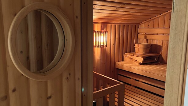 A wooden sauna room with benches and a circular window. - Fantastic vacation home close to nature with sauna (Amelinghausen)