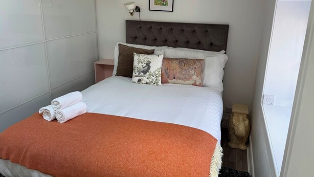 A neatly made bed with a brown throw blanket, a headboard, and a nightstand with a lamp. - Stylish 2BR · Free Parking · Heart of Edinburgh (Edinburgh)
