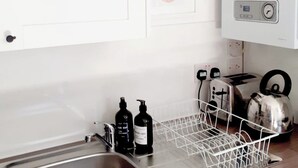 A kitchen with a stainless steel sink, a dish drying rack, two black bottles, a toaster, and a kettle. - Stylish 2BR · Free Parking · Heart of Edinburgh (Edinburgh)