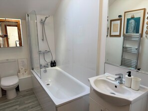Een moderne badkamer met douche, toilet en wastafel.