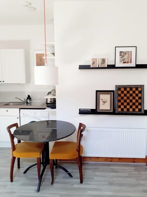 Una cocina moderna con una mesa redonda, sillas, lavavajillas y un radiador.