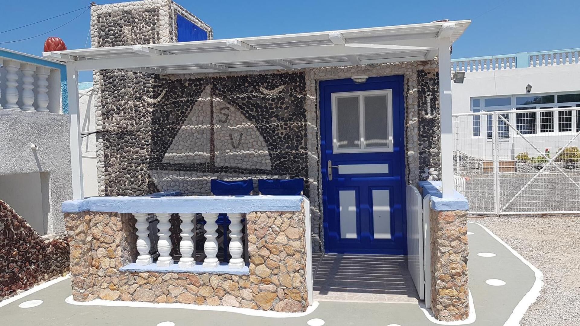 Ein kleines Steinhaus mit einer blauen Tür und einem Balkon.