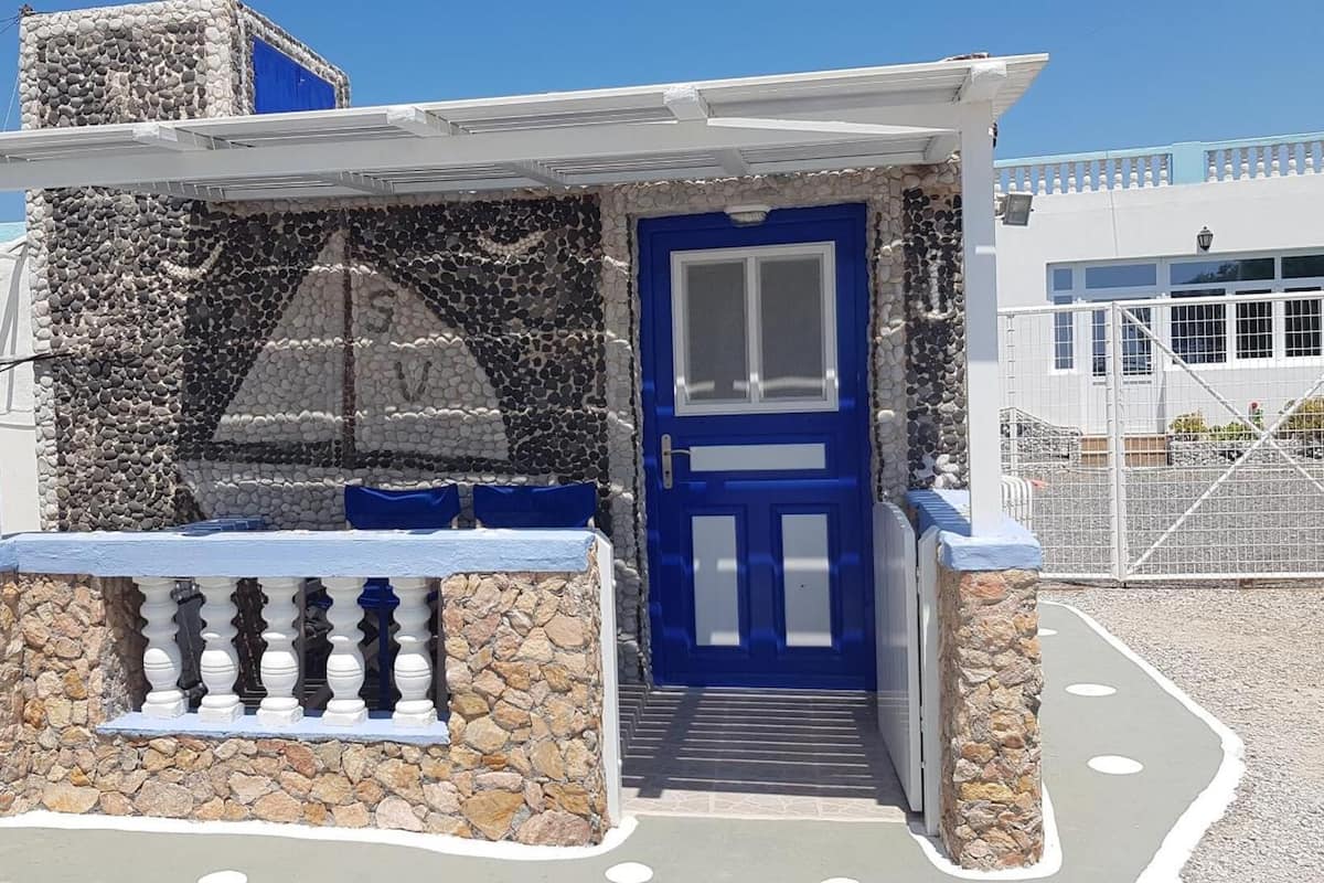 A small stone building with a blue door and a balcony.