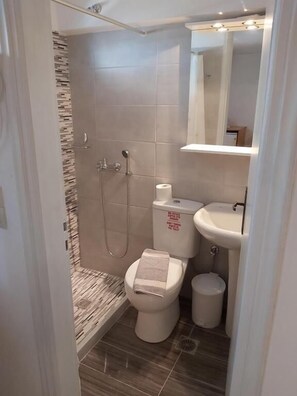 A compact bathroom with a shower, toilet, and sink. - Stavros Beachfront Domes by Booking Kottas (Santorini)