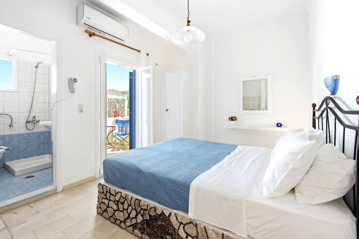 Un dormitorio con cama, un baño con ducha y vistas al exterior.