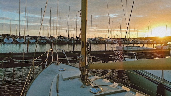 Un port de plaisance oĂč sont amarrĂ©s de nombreux bateaux, un ciel dĂ©gagĂ© et un coucher de soleil.