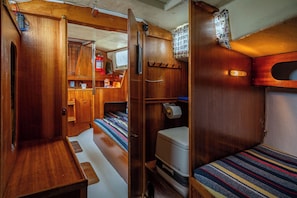 Un intérieur de camping-car compact comprenant deux espaces nuit, un coin cuisine et une petite salle de bain.