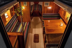 Un interior acogedor y bien iluminado con paredes de madera, una mesa central y bancos a rayas.
