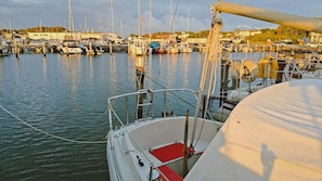 Een jachthaven met aangemeerde boten, dek van een boot met een rode vloer, en een heldere lucht.