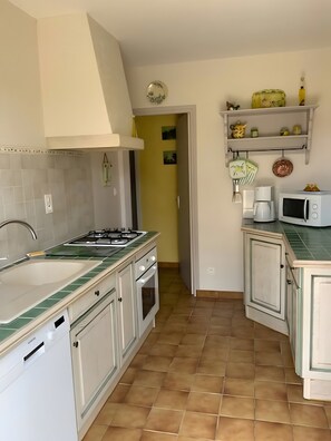 Une cuisine Ă©quipĂ©e dâun Ă©vier, dâune cuisiniĂšre, dâun four Ă micro-ondes et de placards.