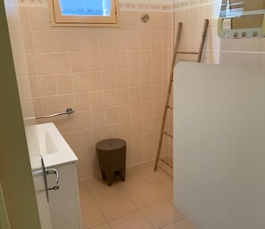 Une salle de bain avec des toilettes, un lavabo et un petit tabouret.
