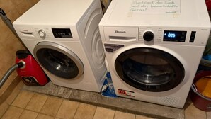 Two front-loading washing machines, one Bosch and one Bauknecht, with a handwritten note on the Bauknecht machine.