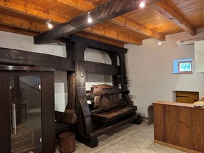 Un intérieur rustique avec des poutres apparentes, un banc en bois, une porte en bois et une petite fenêtre.