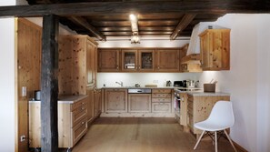 A kitchen with wooden cabinets, a white chair, and a ceiling light fixture.