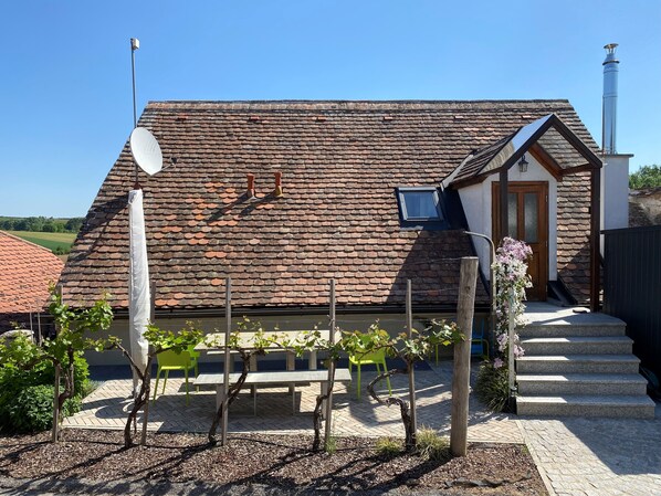 Una casa con techo inclinado, una chimenea y un pequeño porche con escalones.
