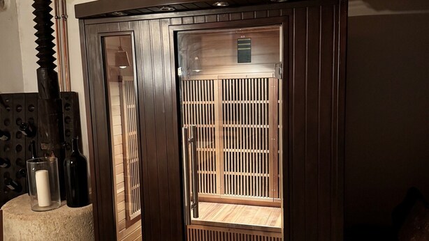 Een sauna met een houten bank, een glazen deur en een houten plafond.