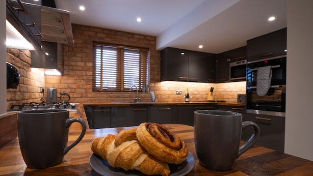 Una cocina con pared de ladrillo, electrodomésticos modernos y un plato de cruasanes.