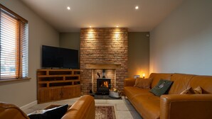 Una sala de estar con chimenea de piedra, televisor, sofá de cuero y mueble de madera para entretenimiento.