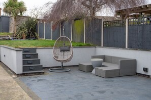 A patio area with a wicker sofa, a hanging chair, and a small table. - The Old Pitman's House - near Sherwood Forest, Spacious modern home (New Ollerton)