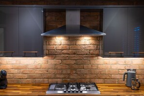 A kitchen with a brick wall, a modern stove, and a coffee maker. - The Old Pitman's House - near Sherwood Forest, Spacious modern home (New Ollerton)