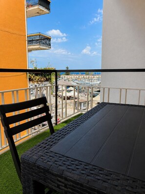 A balcony with a view of a marina, a table, and a chair. - HARBOR ELEGANCE ESTATE (Milazzo)