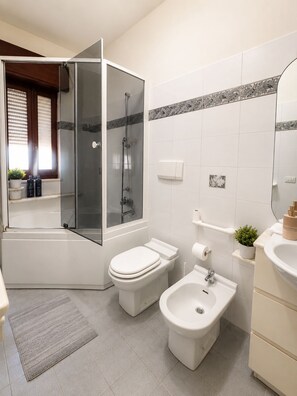 A modern bathroom with a shower, toilet, bidet, and sink. - Vrbo Property (Milazzo)