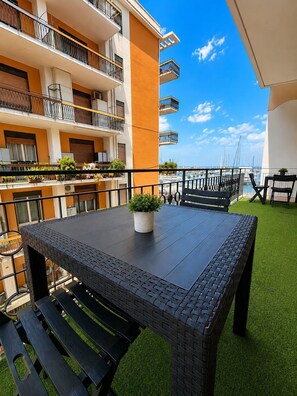 A balcony with a table and chairs, a potted plant, and a view of the sea. - Vrbo Property (Milazzo)
