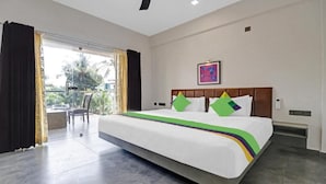 Habitación de hotel con una cama grande, vista por una puerta de cristal y un cuadro en la pared.
