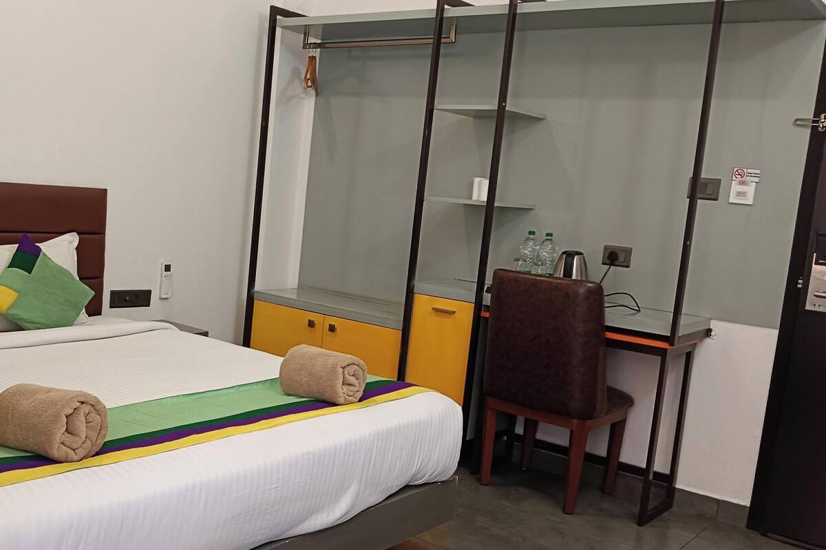 A hotel room with a bed, a desk, a chair, and a wardrobe.