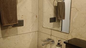A bathroom with a white sink, a mirror, a towel rack, and a soap dispenser.