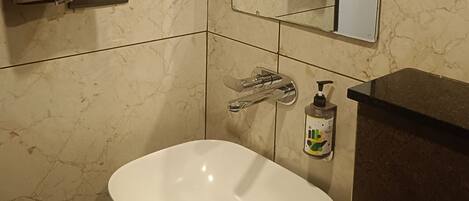 Ein Badezimmer mit einem weißen Waschbecken, einem Spiegel, einem Handtuchhalter und einer Seifenspender.