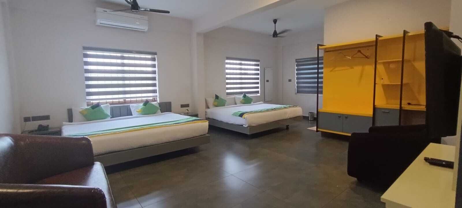 A hotel room with two beds, a wardrobe, a desk, and a chair.