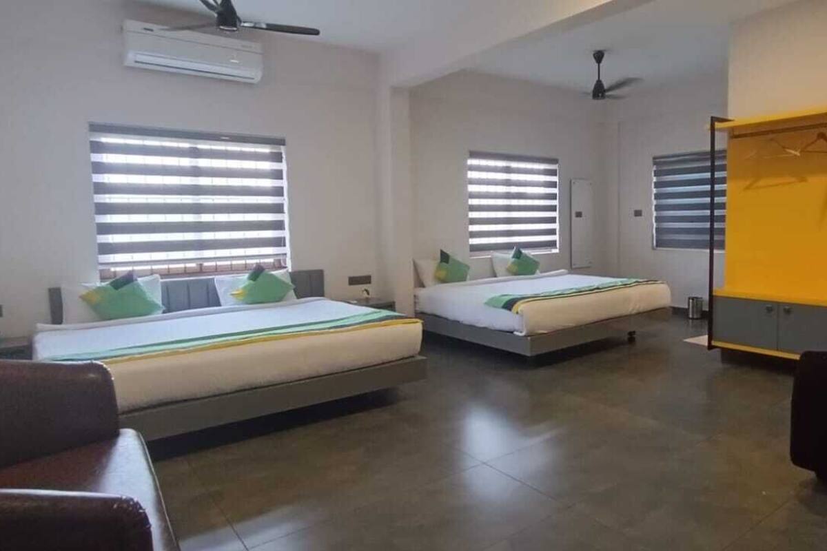 A hotel room with two beds, a wardrobe, a desk, and a chair.