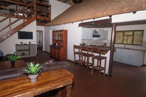 Un vaste espace de vie comprenant une table à manger en bois, un canapé et un escalier.