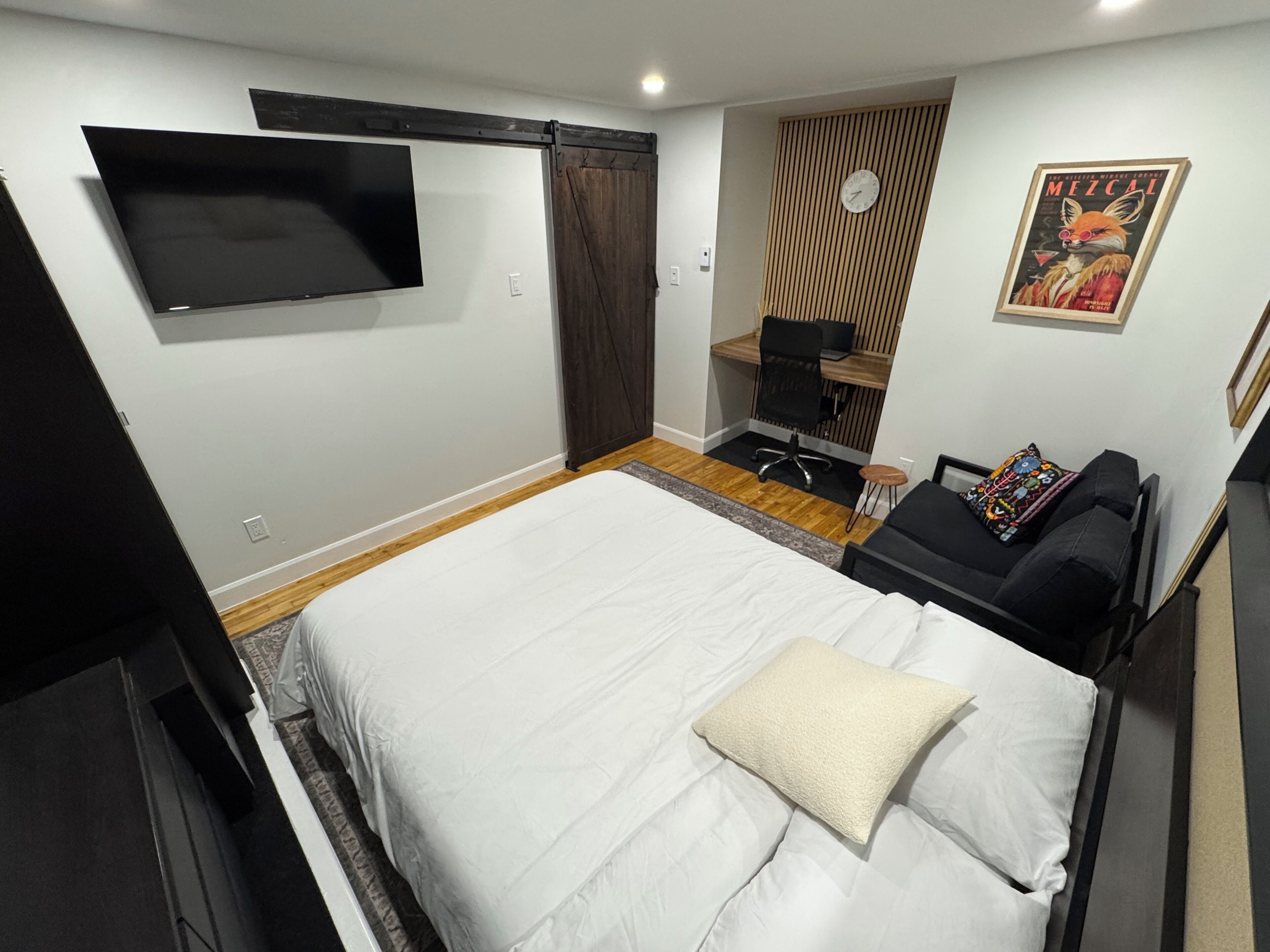 A bedroom with a bed, a desk, a chair, a TV, and a poster on the wall.