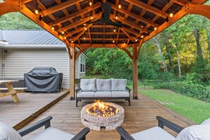 A covered deck with a fire pit, a sofa, and a table. - Spillway Oasis- Plunge Pool & Fire Pit (Dothan)