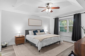 A bedroom with a bed, bedside lamps, a ceiling fan, a window with curtains, and a nightstand. - Spillway Oasis- Plunge Pool & Fire Pit (Dothan)