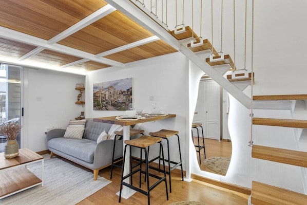A modern interior with a wooden staircase, a dining area, and a sofa. - Scandinavian Loft Escape in JVC Dubai (Dubai)