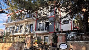 Un bâtiment à deux étages, doté d’un mur en pierre, d’une porte en métal et d’une enseigne indiquant « Lotus Hotel ».