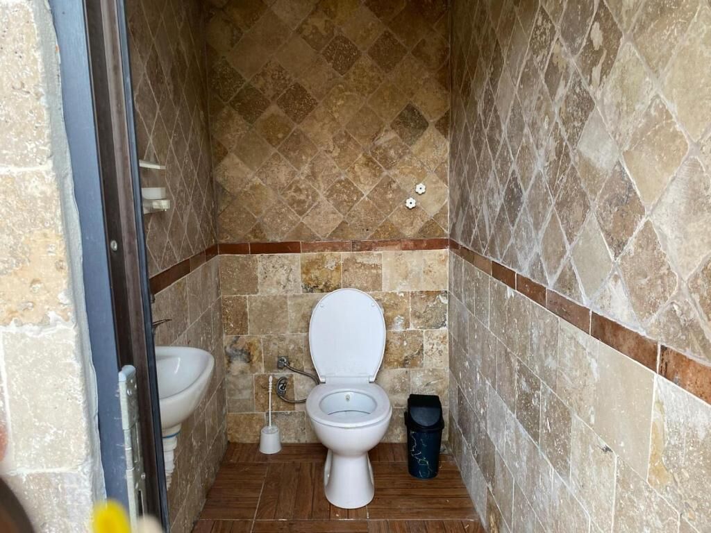 Un baño pequeño con inodoro, bidé y un cubo de basura.
