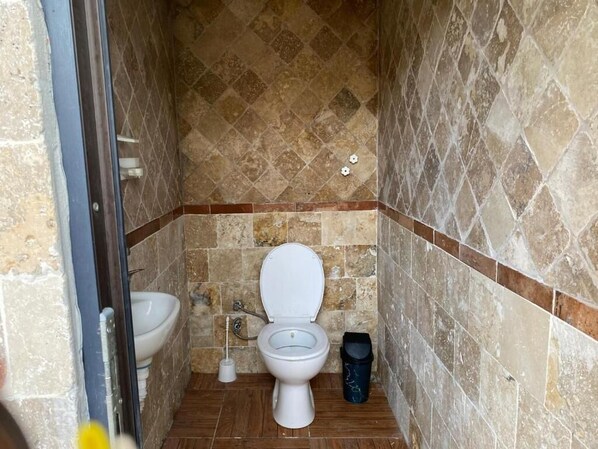Un baño pequeño con inodoro, bidé y un cubo de basura.