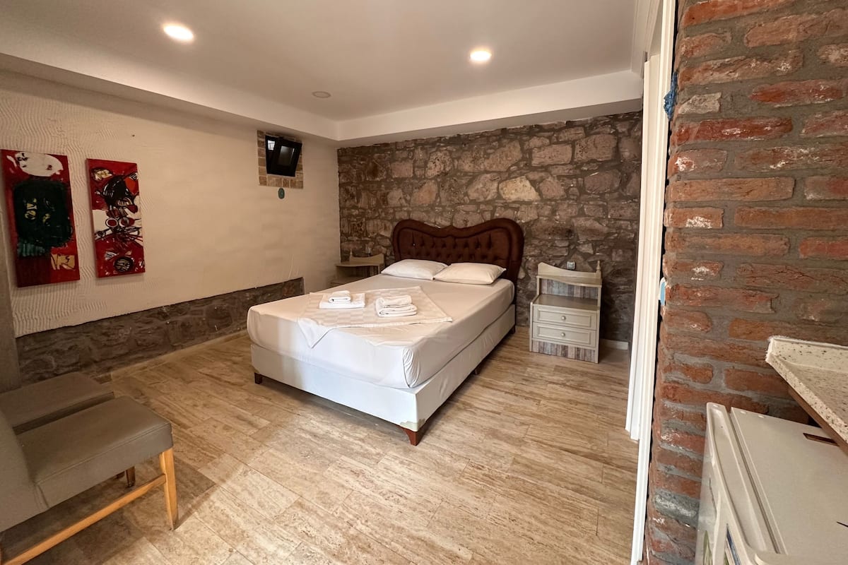Une chambre avec un lit, une télévision, un mur en pierre et un plancher en bois.