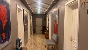 Un couloir doté d’un plancher en bois, de portes blanches et d’œuvres d’art accrochées aux murs.