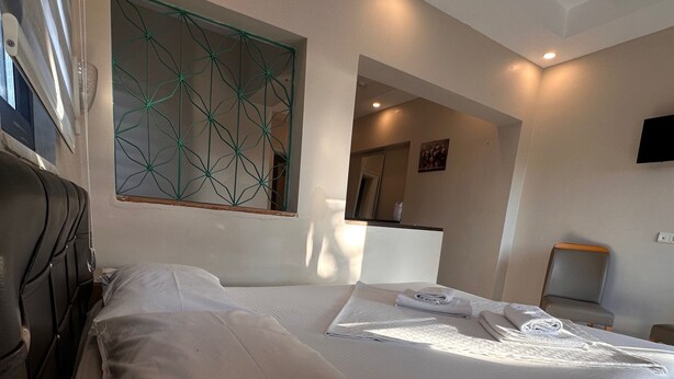 Une chambre d’hôtel comprenant un lit, une tête de lit, une œuvre d’art accrochée au mur, un miroir et une table de chevet.